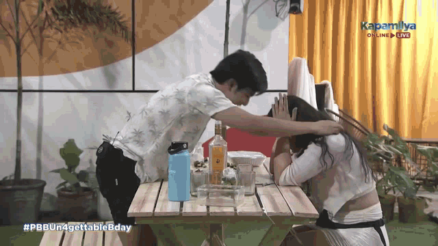 a man covering a woman 's face while sitting at a picnic table with the caption #pbbun4gettable8day