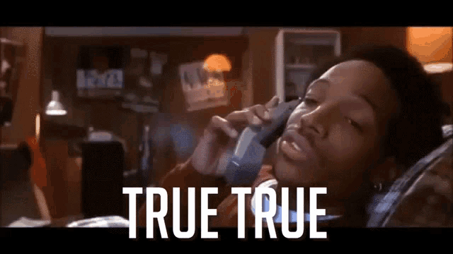 a man laying on a couch talking on a cell phone with the words true true written below him