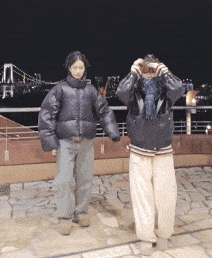 a couple of people standing next to each other in front of a city at night