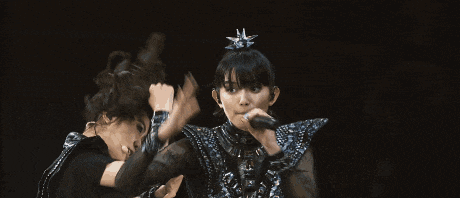 a group of women are dancing on a stage with their hands in the air