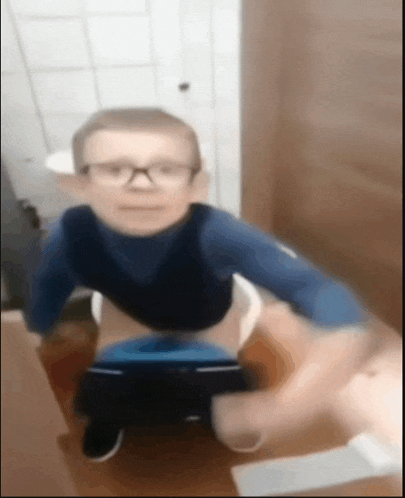 a blurry picture of a child wearing glasses sitting on a toilet
