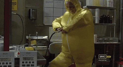 a man in a yellow protective suit is standing in front of a clock that says 9 02 on it
