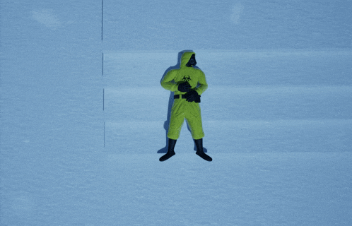a person in a yellow biohazard suit is laying in the snow