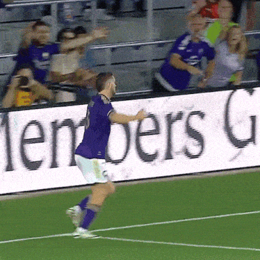 a man in a purple jersey with the number 8 on the back is running on a soccer field
