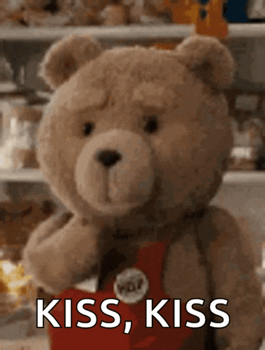a teddy bear is holding a red heart and says kiss kiss .