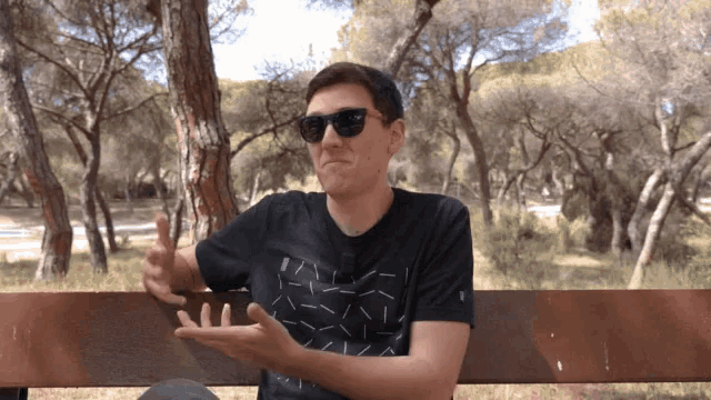 a man wearing sunglasses and a black shirt is sitting on a bench