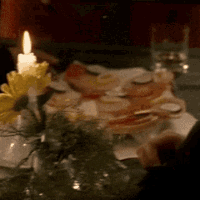 a candle is lit on a table with flowers and food