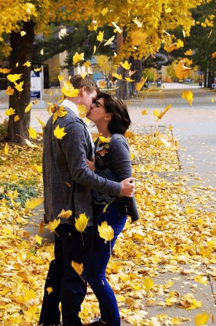 a man and a woman kissing in front of a sign that says ' a ' on it