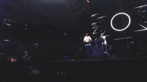 two men are standing in front of a large crowd at a concert