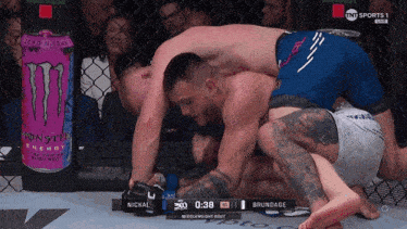 two men are wrestling in a cage with a can of monster energy drink in the background