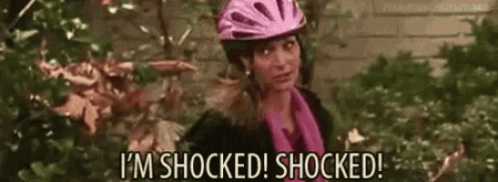 a woman wearing a bicycle helmet is standing in front of a brick wall .