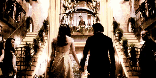 a bride and groom are holding hands while walking down a set of stairs