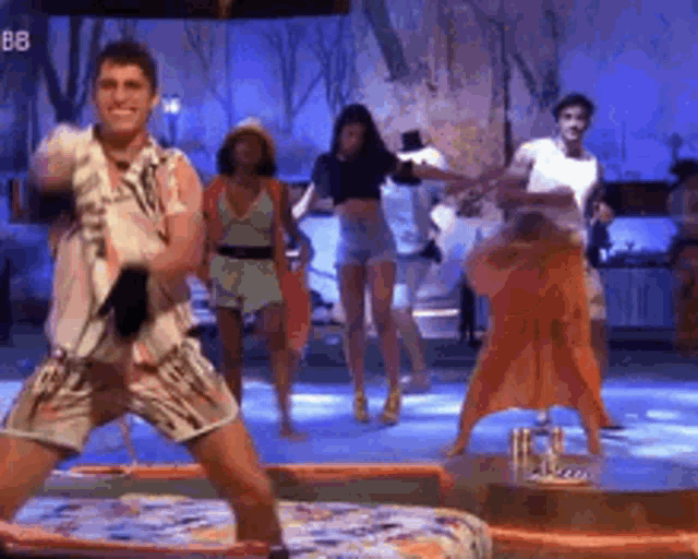a group of people are dancing on a stage with the letters bb in the background .
