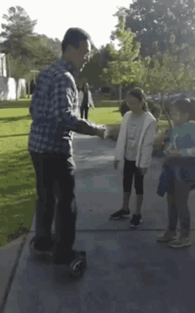 a man in a plaid shirt is shaking hands with two girls