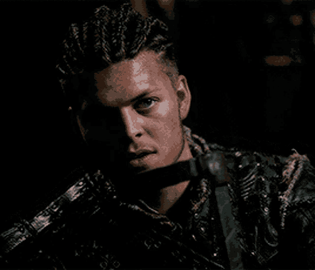 a man with dreadlocks is holding a knife in his mouth in a dark room .