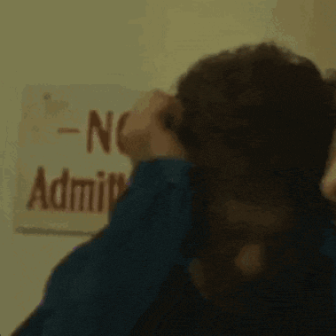 a man in a blue shirt is covering his ears with his hands while making a funny face