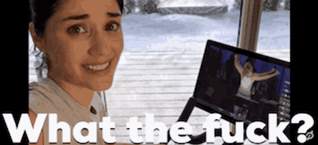 a woman is smiling in front of a computer screen with the words what the fuck written on it .
