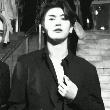 a black and white photo of a man in a suit adjusting his jacket