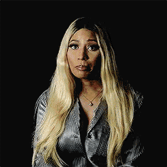 a woman with long blonde hair is wearing a striped jacket and making a surprised face .
