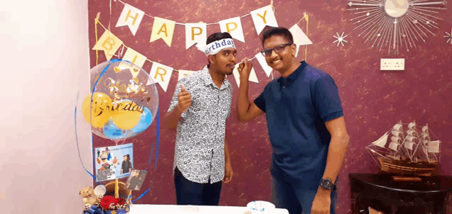 a man wearing a headband that says happy birthday stands next to another man