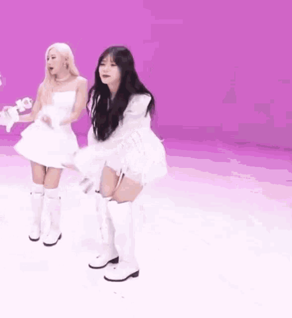 two girls in white dresses and white boots are dancing on a purple background .