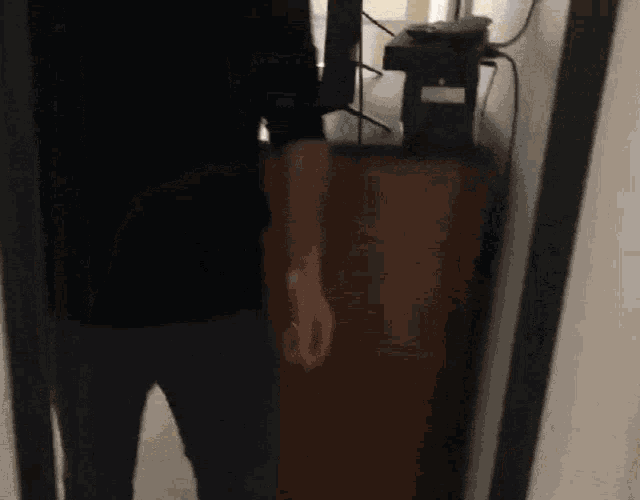a man in a black shirt is standing next to a brown cabinet