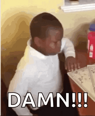 a little boy is sitting at a table and making a funny face with the words `` damn !!! '' .