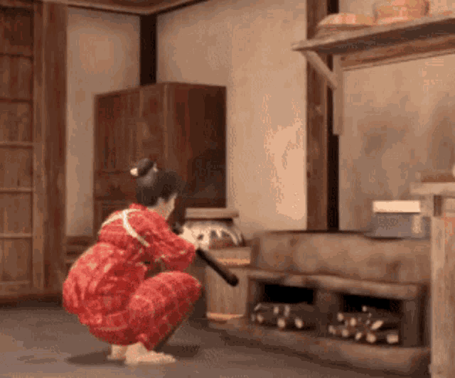 a woman in a red robe is squatting on the floor holding a sword