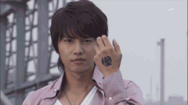 a man wearing a pink shirt has a tattoo on his arm