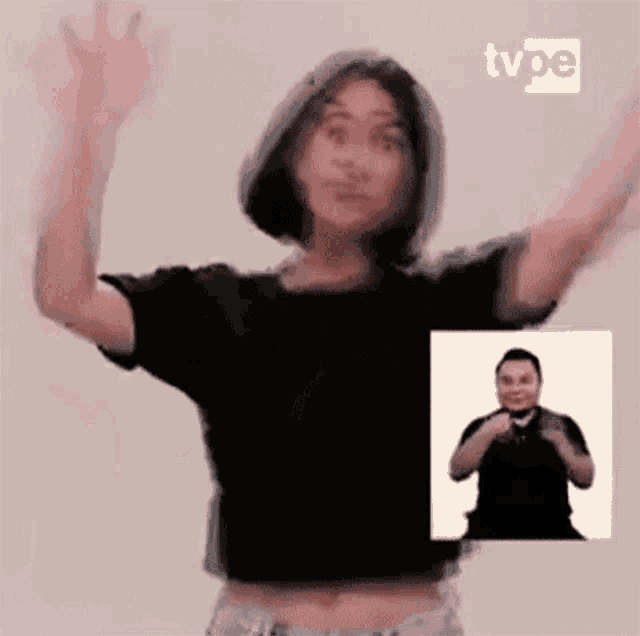 a woman in a black crop top is dancing in front of a man in a black shirt .