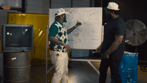 two men standing in front of a white board that says crew on it