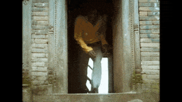 a man in a yellow shirt stands in a doorway