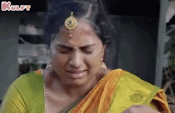 a woman in a sari is crying while holding a baby in her arms .