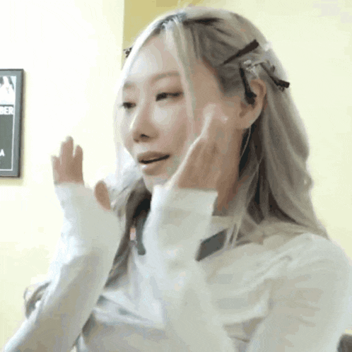 a woman with long blonde hair is making a funny face while wearing a white sweater .