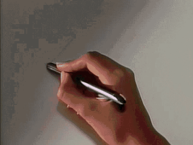 a person is holding a pen in their left hand and writing on a piece of paper .