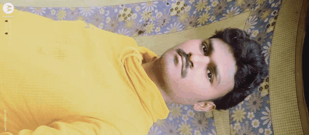 a man in a yellow sweater laying on a bed