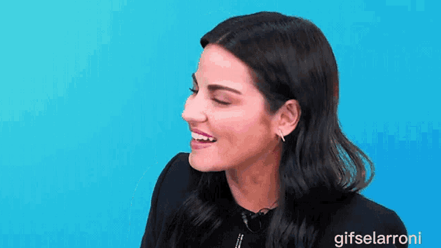a woman is smiling in front of a blue background that says gifselaroni on the bottom