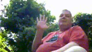 a man in a red shirt with a bird on it is waving his hand