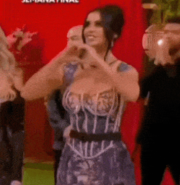 a woman in a corset dress is making a heart shape with her hands .