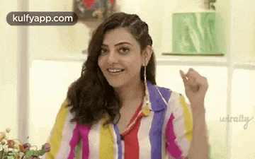 a woman in a colorful striped shirt is making a funny face while sitting at a table .