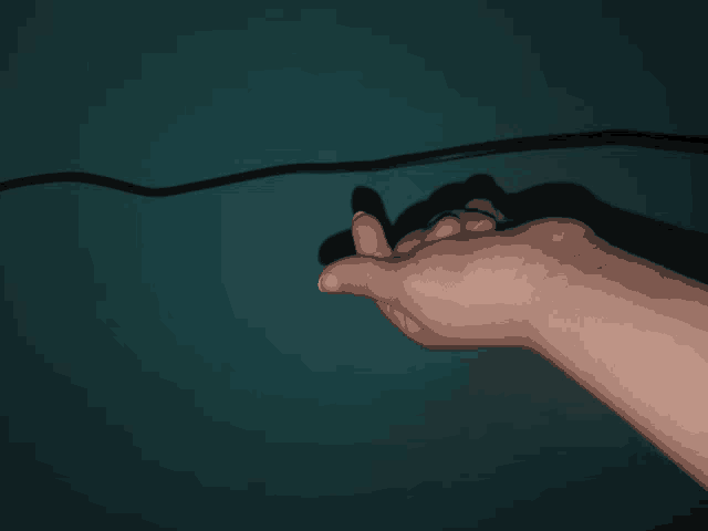 a person 's hand is against a blue wall and their thumb is visible
