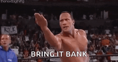the rock is standing in a ring with his fist in the air .