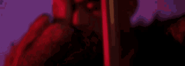 a man with a beard is holding his head in a red light .