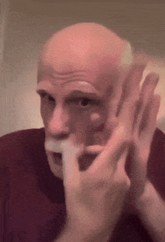 a bald man with a beard is being shaved by a woman .