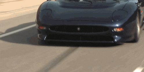 a black sports car is driving down a street