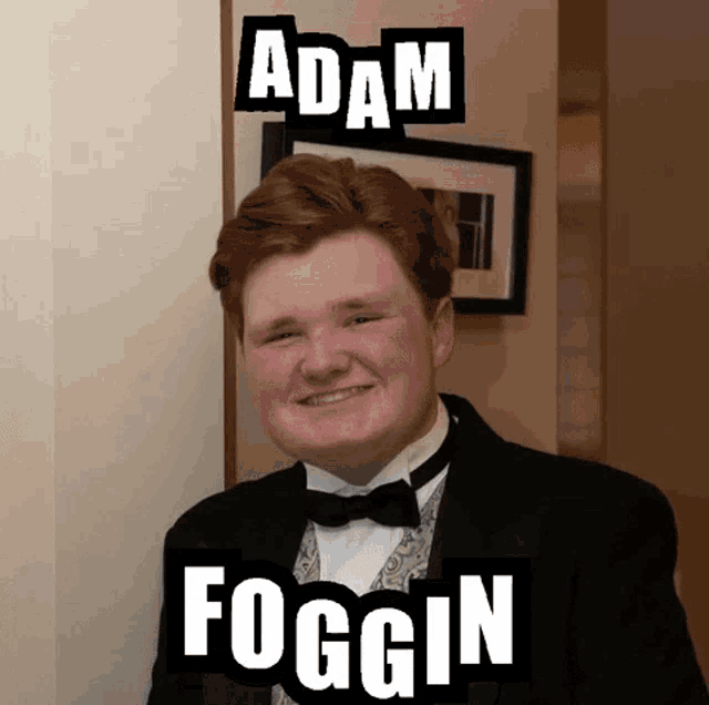 a young man in a tuxedo is standing next to a wall with the words adam foggin on it