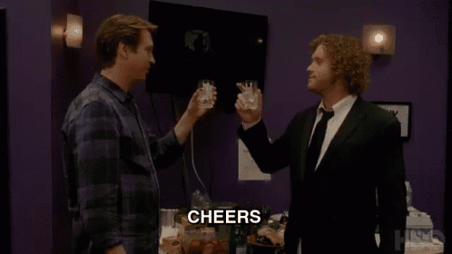 two men are toasting with whiskey and the word cheers is on the bottom of the screen