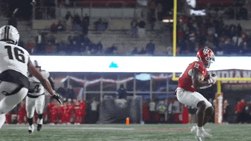 a football player wearing a red jersey with the number 19 on it is running with the ball .