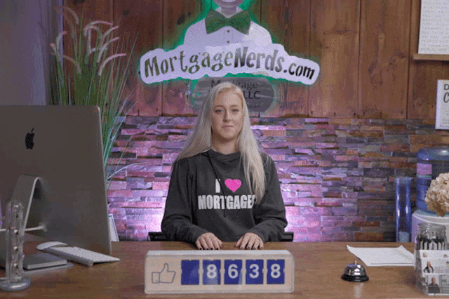 a woman sitting at a desk with a sign that says mortgage nerds.com