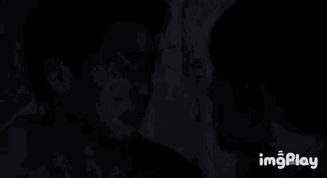 two men are kissing each other in the dark in a dark room .